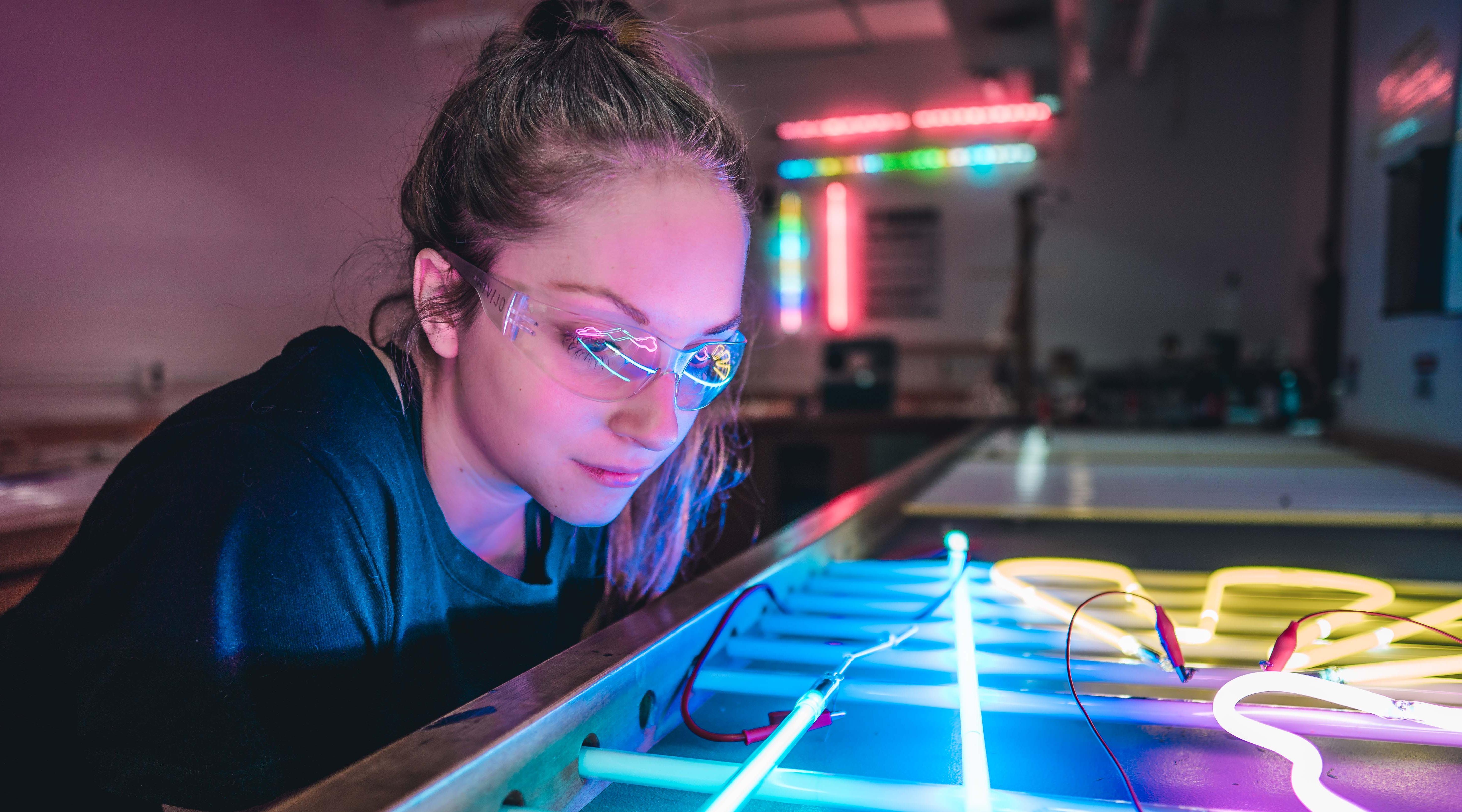 Art student in neon light shop.